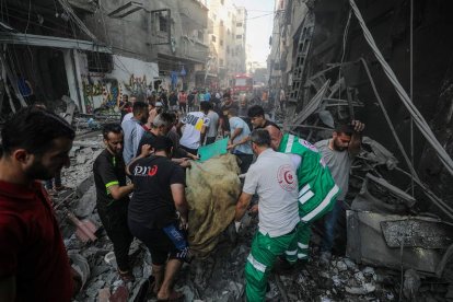 Retiran un cuerpo en el lugar de un ataque de Israel en el campo de refugiados de Al-Shati. MOHAMMED SABER