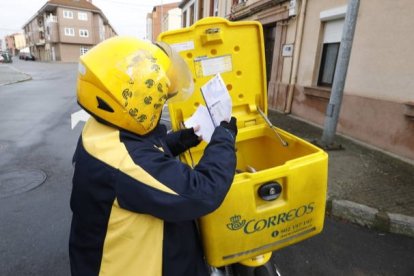 Una cartera de Correos en León revisa correspondencia. MARCIANO PÉREZ