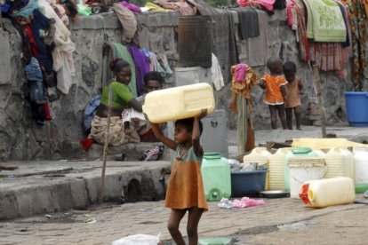 Una niña huérfana carga con un bidón para el agua en Bombai (India).