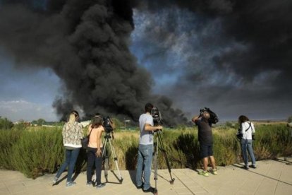 Unos periodistas toman imágenes de la gran columna de humo producida este viernes en un polígono de Chiloeches, Guadalajara.