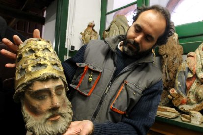 Un trabajador del Centro de Restauración y Conservación, con la cabeza de una talla.