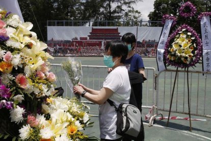 Dos mujeres colocan flores en el memorial a las víctimas de Tiananmen, en Hong Kong.