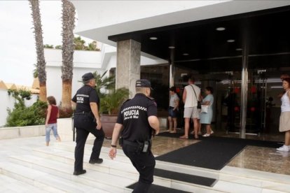 Dos agentes de la Policía Local de Lloret entran en el hotel Marina Sand, en la mañana de este viernes, para verificar que se está llevando a cabo el desalojo del establecimiento.