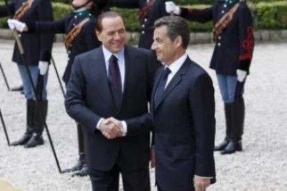 El primer ministro italiano, Berlusconi, estrecha la mano del presidente francés, Sarkozy.