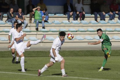 Diego Peláez golea el balón ante dos defensas rivales. FERNANDO OTERO