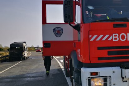 Vehículo de los bomberos con la furgoneta calcinada al fondo. BOMBEROS DE LEÓN