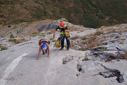 Un agente ayuda a uno de los montañeros a concluir su escalada sano y salvo en Peña Llana. GREIM