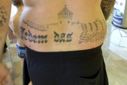 Fotografía facilitada del tatuaje del condenado que reza "Jedem das Seine" ( lit. a cada uno lo suyo) bajo lo que parece el campo de exterminio de Auschwitz.