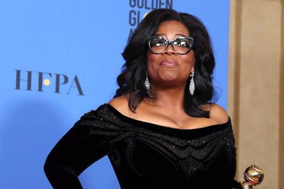 Oprah sostiene un premio en los Globos de Oro