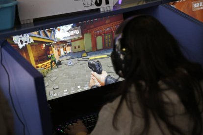 Una joven juega con una pistola virtual frente a la pantalla de un videojuego.