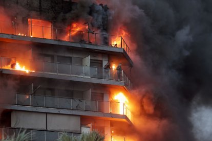 Dos personas aguardan en el balcón a ser rescatadas en el incendio declarado sobre las cinco y media de esta tarde en un quinto piso de un edificio de viviendas de Valencia que ha afectado totalmente al inmueble y se ha propagado a otro anexo.