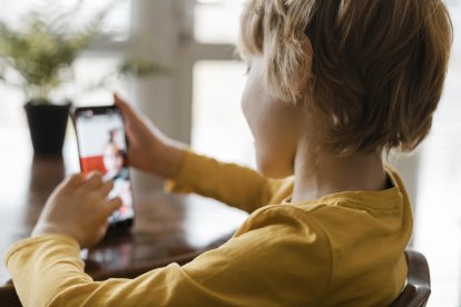 Niño sonriente tocando la pantalla de su smartphone.