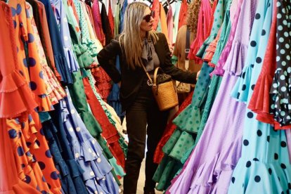 Una mujer entre trajes de flamenca hoy en una tienda en Sevilla.