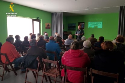 Un guardia civil da una charla sobre seguridad a personas mayores.