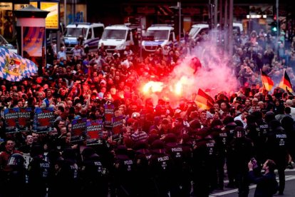 Manifestantes de derecha prenden bengalas mientras enfrentan a la policía antidisturbios durante una manifestación en el lugar donde apuñalaron a un hombre la noche del 25 de agosto de 2018, en Chemnitz (Alemania) hoy, lunes 27 de agosto de 2018. La muerte de un hombre tras una pelea en una fiesta popular en el este de Alemania desató lo que el Gobierno de la canciller Angela Merkel calificó hoy de 