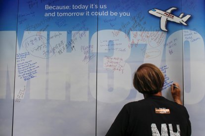 Fotografía de archivo donde una mujer escribe un mensaje dedicado para los pasajeros desaparecidos del avión MH370 de Malaysia Airlines, en el Aeropuerto Internacional de Kuala Lumpur, Malasia, 6 de marzo de 2016. 
                      EFE/ Fazry Ismail