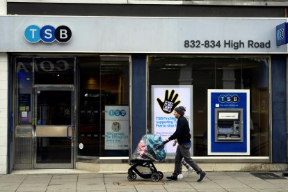 Una pareja camina junto a una sucursal del banco británico TSB en Londres, Reino Unido. EFE/Neil Hall/Archivo