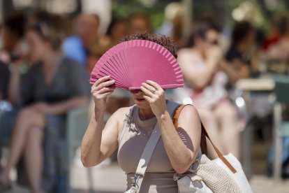 Una mujer se protege con un abanico del sol y del calor en Valencia. EFE/Ana Escobar