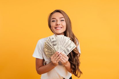 Joven sonriente con un abanico de billetes.