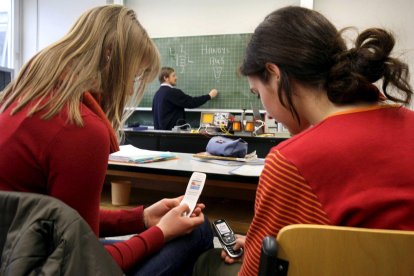 Imagen de archivo de dos estudiantes usando sus teléfonos móviles durante una clase en un instituto. EFE/ MARCUS FUERER