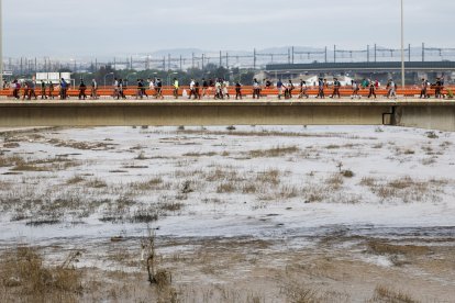 Voluntarios cruzan el río Turia desde Valencia en dirección a Paiporta para colaborar en las labores de limpieza y reconstrucción de las zonas afectadas por la dana, este domingo. EFE/Biel Aliño