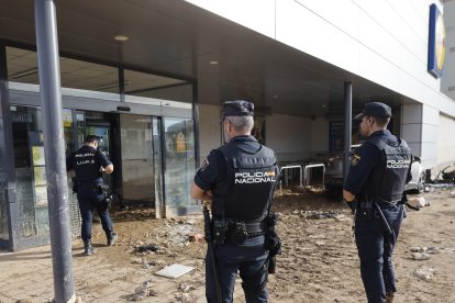 Agente de la Policía Nacional vigilan un comercio en Alfafar (Valencia), este viernes. EFE/ Kai Försterling