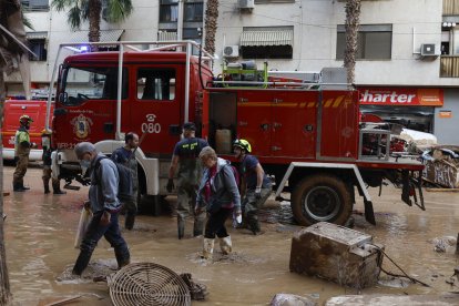 Imagen de archivo de efectivos del cuerpo de Bomberos y voluntarios durante las labores de limpieza en una calle en Catarroja.
                       EFE/J.J. Guillén