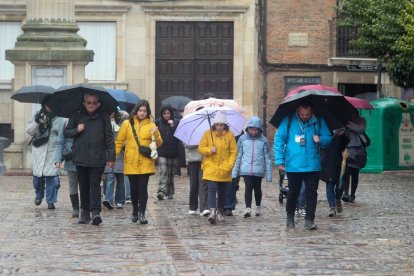 Un grupo de turistas escuchaba ayer a uno de los guías de León, en medio de la lluvia y la nieve.