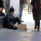 Un indigente pide ayuda a los traseúntes en una calle de Barcelona, ayer.