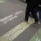 Madre e hijo pasean sobre unos eslóganes pintados frente al colegio de La Virgen.