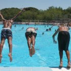 Tres jóvenes se lanzan a la piscina en una intensa jornada de calor veraniego. KIKO HUESCA