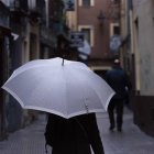 Una mujer se protege de la lluvia con un paraguas.