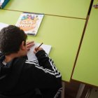 Un niño escribe en un cuaderno en un centro de menores.