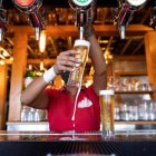 Una camarera sirve unas cervezas en un bar.