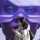 Una mujer pasa por delante de un cartel del Mobile World Congress de Barcelona.