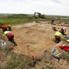 Trabajadores en el yacimiento de Lancia con una excavadora al fondo.