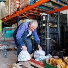Uno de los voluntarios del Banco de Alimentos de León, ayer con las bolsas que se distribuyen a las familias. La reina Sofía, en el congreso de Santander, ayer.