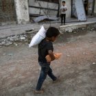 Un niño recoge harina y pan en Gaza.