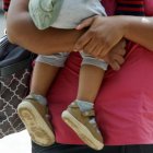 Una mujer sostiene a un bebé en brazos mientras pasea por la calle.