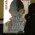 Una joven observa un cartel contra el acoso escolar.