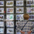 Una mujer mira la oferta de pisos en una inmobiliaria.