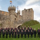 Miembros del grupo coral posan frente al castillo.