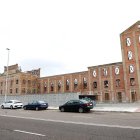 La fachada de la antigua Azcarera Santa Elvira luce ya sin andamios después de 16 años amparados los muros. A la derecha, imagen de las máquinas que trabajan este domingo para adelantar la entrega del trampantojo de lo que iba a ser el Palacio de Congresos de León.