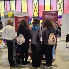 Cuatro chicas se acercan a Diaconía en la Expojoven para participar en el juego interactivos con información sobre la trata.