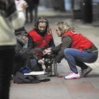 Dos voluntarias de Cruz Roja ofrecen una bebida caliente a una persona en la calle.