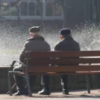 Dos personas mayores descansan en un banco del parque de San Francisco de León