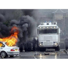 Un coche arde mientras la policía contempla la escena en Ardoyne, el jueves.