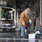 Un hombre recibe una limosna en medio de la tormenta de nieve en Huesca.
