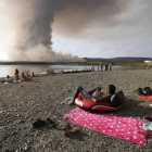 Bañistas observan la columna de humo procedente del fuego que asoló el pinar de Villameca.