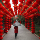Una mujer pasea bajo la lluvia y entre las características lamparillas rojas en el popular parque Ditan, en Pekín. ROMAN PILYPEY